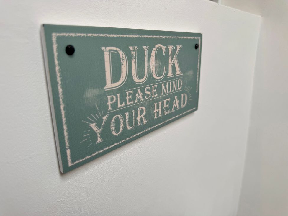 A sign that says 'Duck Please Mind Your Head' at Railway Cottage Penybontfawr