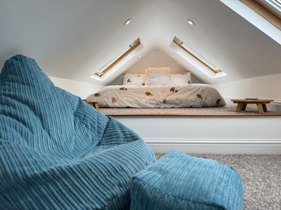 A loft space with a bed and a bean bag at Railway Cottage in Penybontfawr