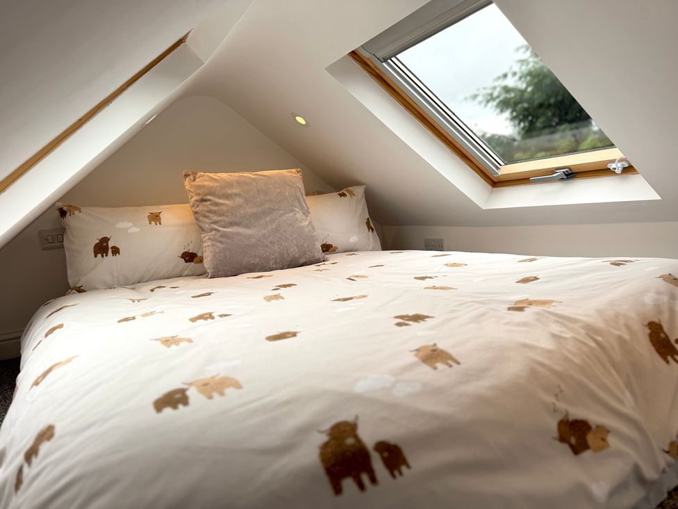 A bedroom with a bed and window at Railway Cottage in Penybontfawr