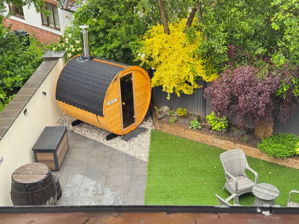 A garden with a sauna, barrel, and outdoor furniture at Railway Cottage in Penybontfawr