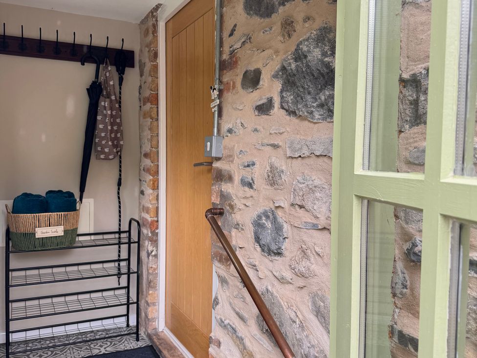 A hallway with a door and coat rack at Railway Cottage in Penybontfawr