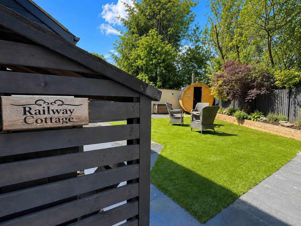 A garden with chairs and barrel sauna at Railway Cottage in Penybontfawr
