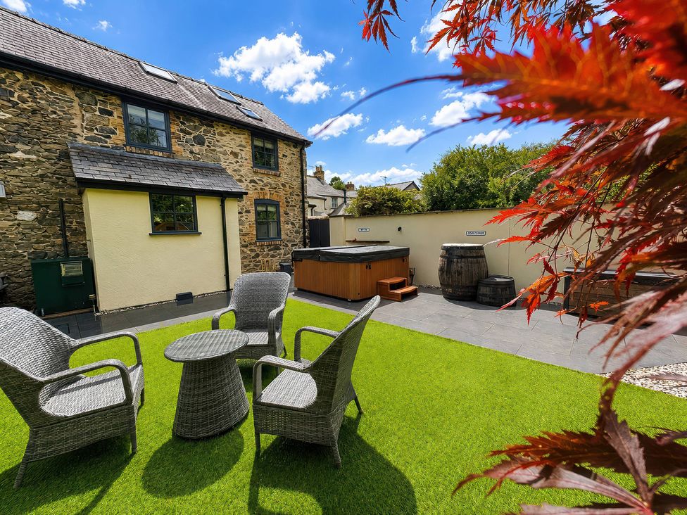 A garden with a hot tub and seating area at Railway Cottage in Penybontfawr
