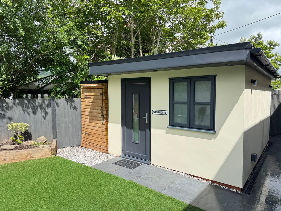 A wash house structure with a pathway and grass at Railway Cottage in Penybontfawr