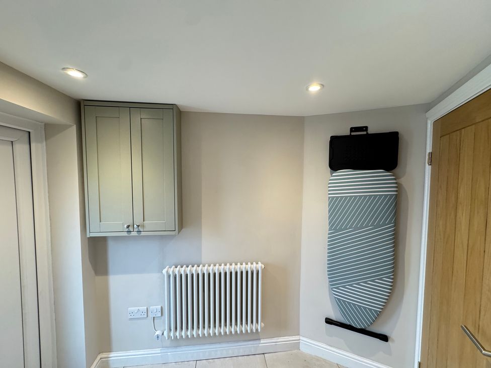 A utility room with shelves and an ironing board at Railway Cottage in Penybontfawr