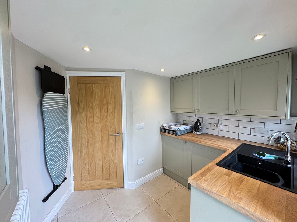 A kitchen with an ironing board and sink at Railway Cottage in Penybontfawr