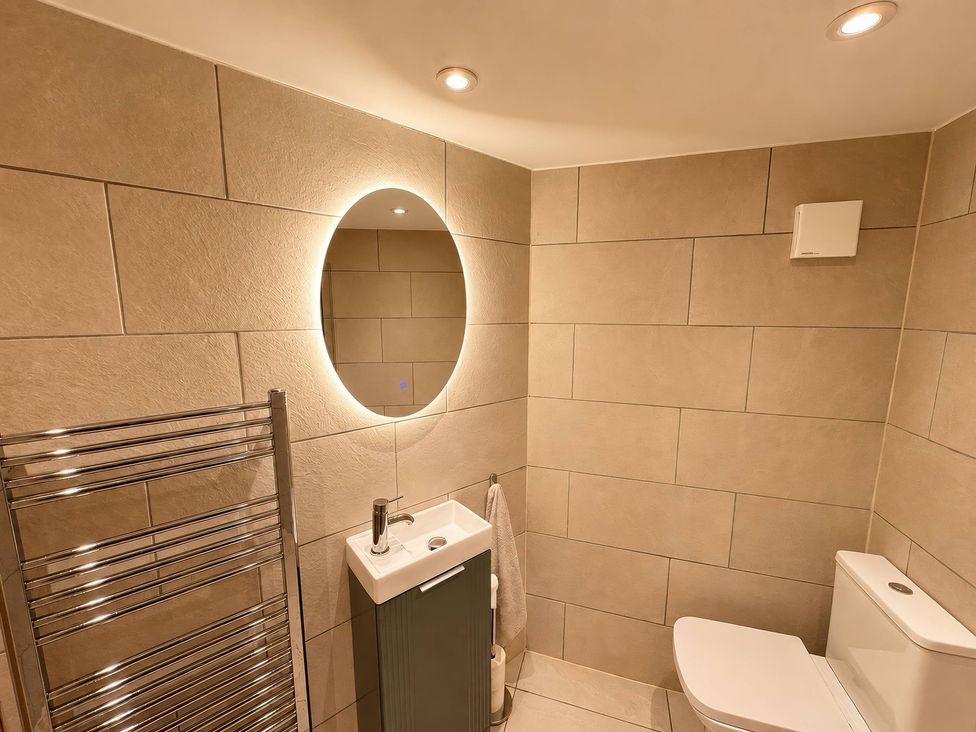 A bathroom featuring a sink, toilet, mirror, and towel rail at Railway Cottage in Penybontfawr