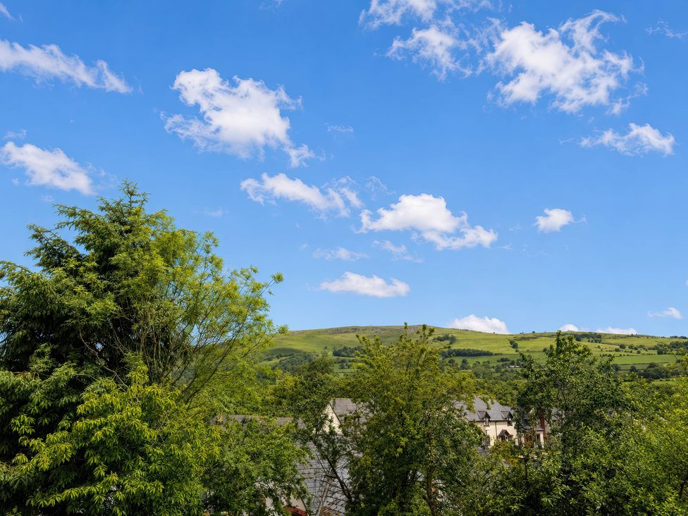 A view of hills and trees under a blue sky at Railway Cottage Penybontfawr