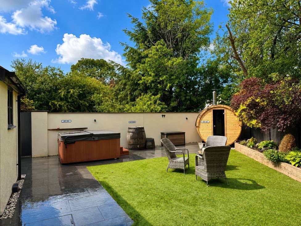 A garden with a hot tub, sauna and seating area at Railway Cottage in Penybontfawr
