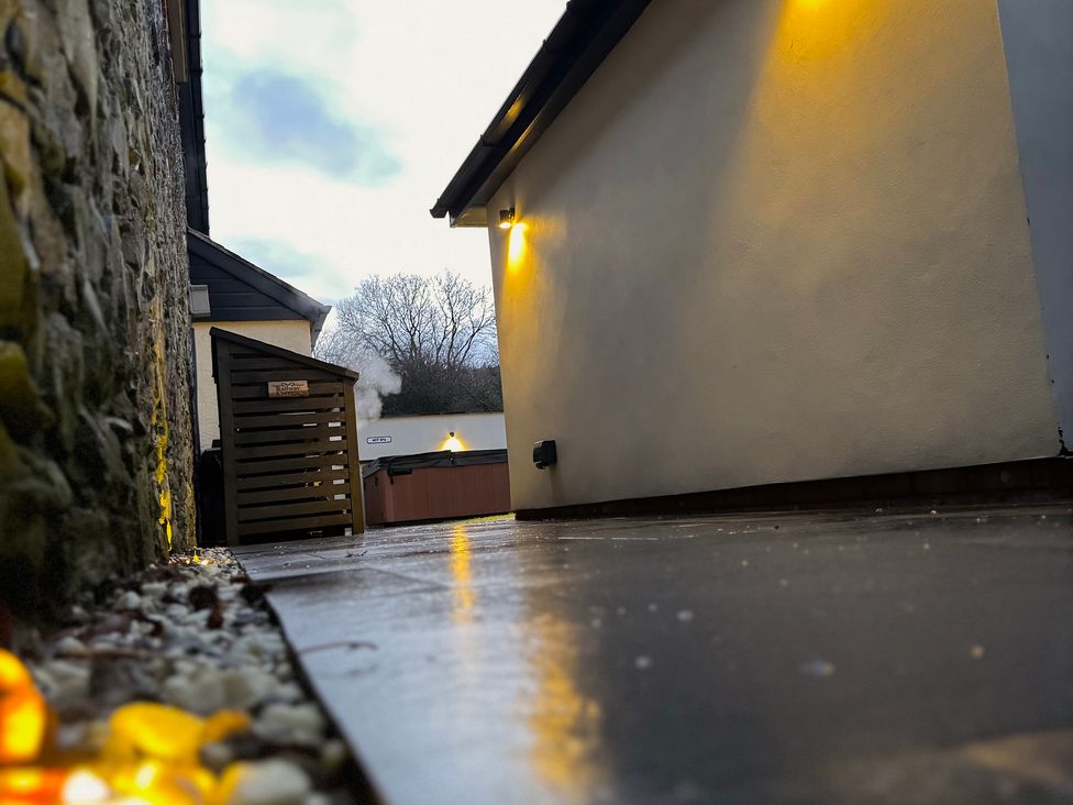 An outdoor area with stone wall and a hot tub at Railway Cottage in Penybontfawr