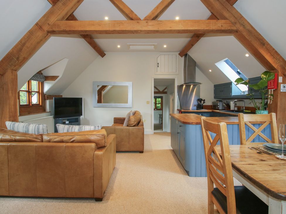 A living room with a sofa, tv, and kitchen area at Pultheley Cottage in Hyssington near Churchstoke