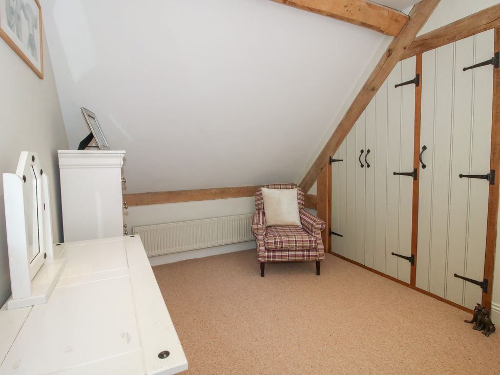 A bedroom with an armchair and vanity at Pultheley Cottage Hyssington near Churchstoke
