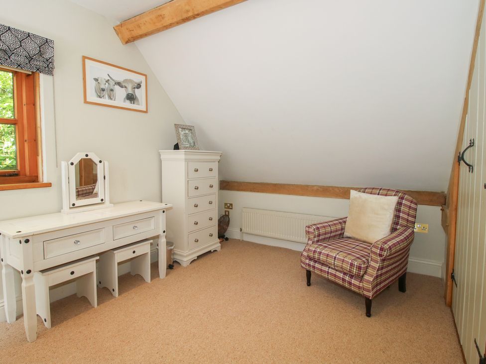 A bedroom with a dresser and chair at Pultheley Cottage in Hyssington near Churchstoke