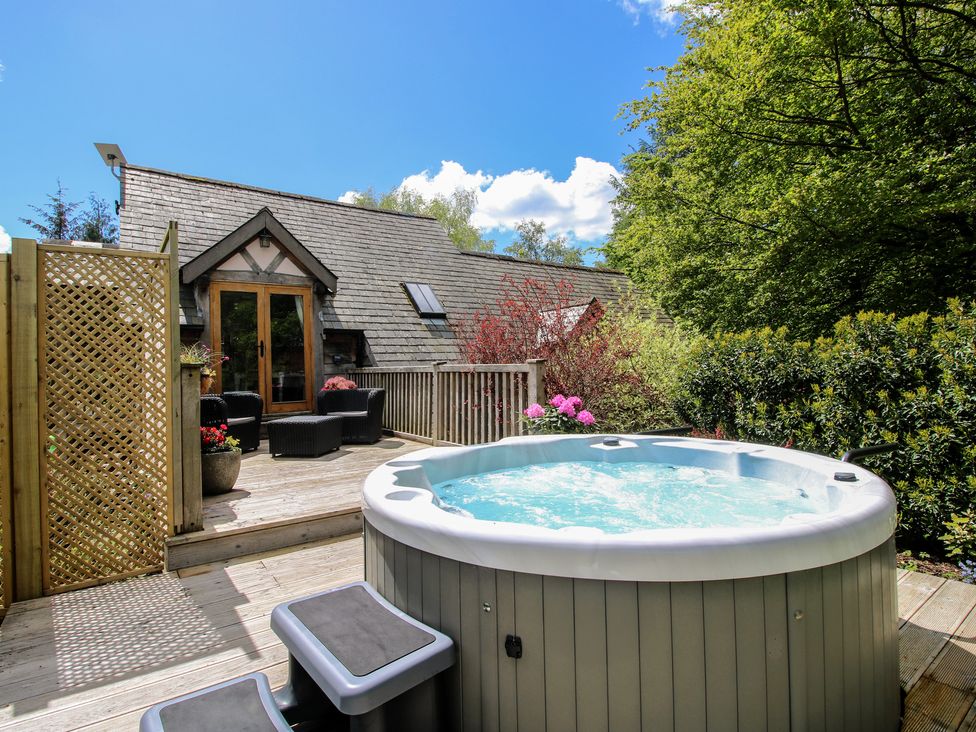 A hot tub on decking with seating area at Pultheley Cottage Hyssington near Churchstoke
