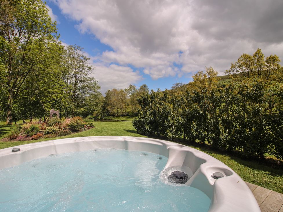 A hot tub near trees and grass at Pultheley Cottage in Hyssington near Churchstoke