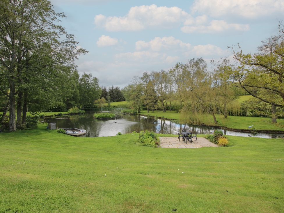 A garden with a pond and patio seating area at Pultheley Cottage Hyssington near Churchstoke