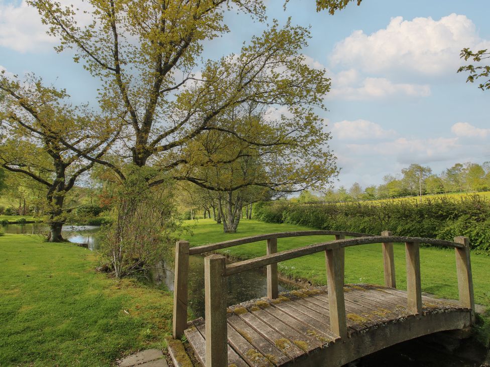 A bridge over a stream in a garden at Pultheley Cottage Hyssington near Churchstoke