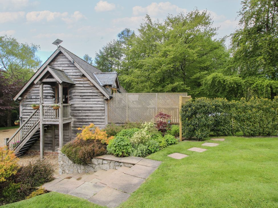 A wooden building with a staircase and garden at Pultheley Cottage Hyssington near Churchstoke