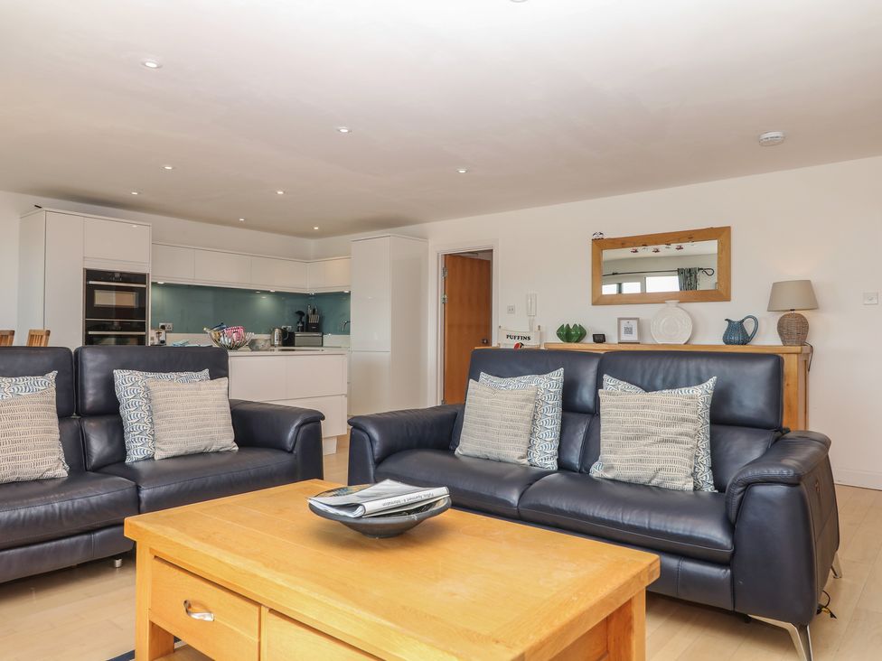 A living room with sofas and kitchen area at 4 Burgh Island Causeway in Bigbury