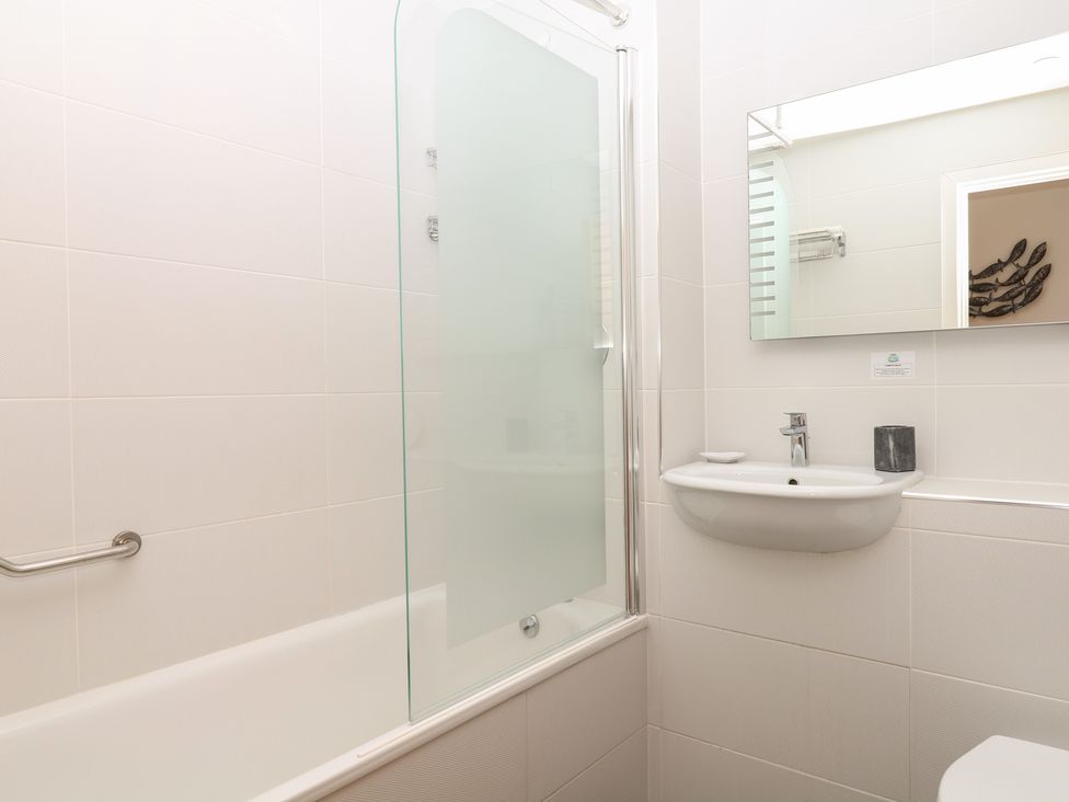 A bathroom with a bathtub, shower, sink, and mirror at 4 Burgh Island Causeway, Bigbury