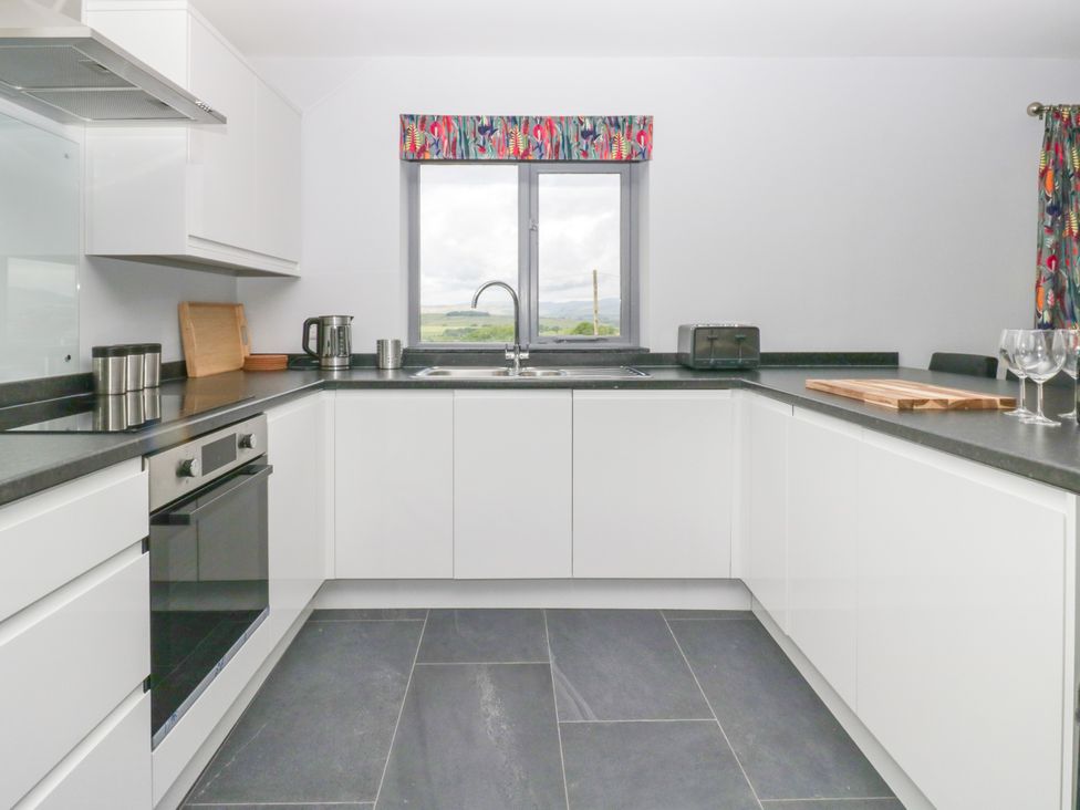 A kitchen with appliances and a window at Fell View Cottage in Lambrigg near Kendal