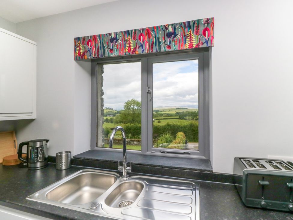 A kitchen with sink and window overlooking the countryside at Fell View Cottage Lambrigg near Kendal