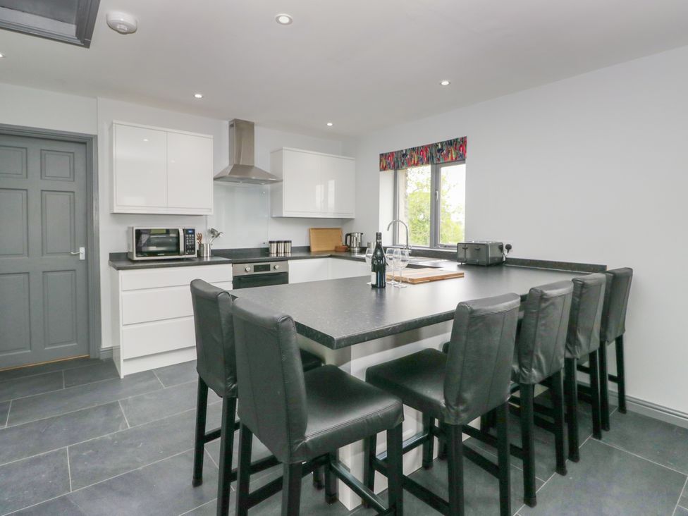 A kitchen with bar stools and appliances at Fell View Cottage in Lambrigg near Kendal