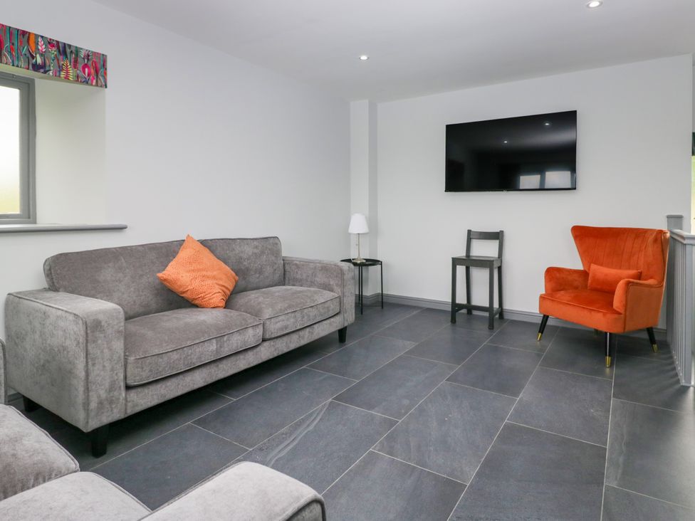 A living room with a sofa, chair, table, and television at Fell View Cottage in Lambrigg near Kendal