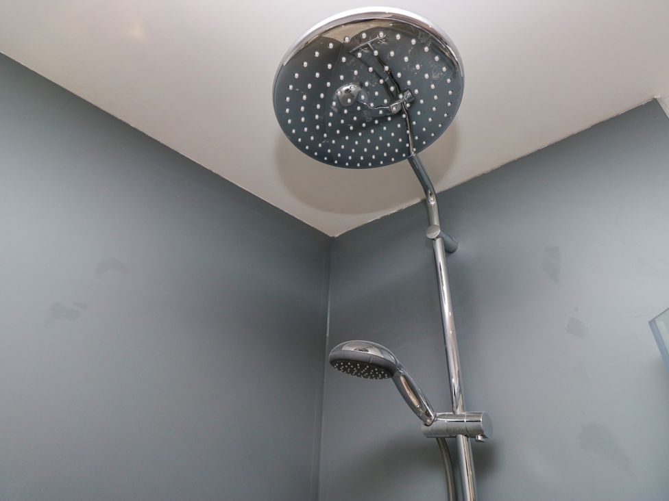 A shower with a ceiling-mounted showerhead and a handheld shower at Fell View Cottage Lambrigg near Kendal