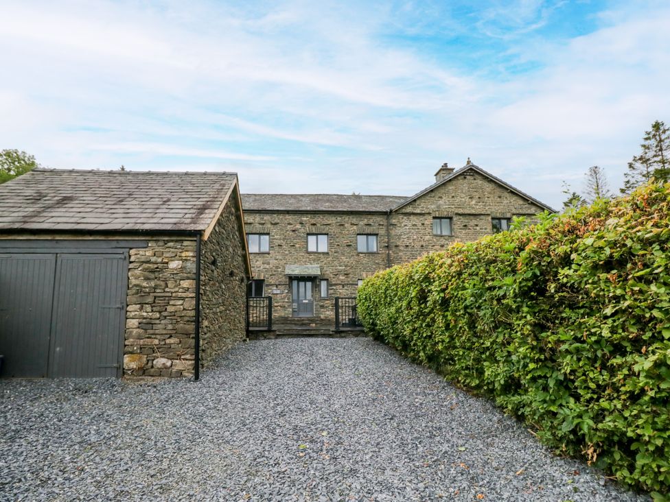 A building with a garage and gravel area at Fell View Cottage in Lambrigg near Kendal