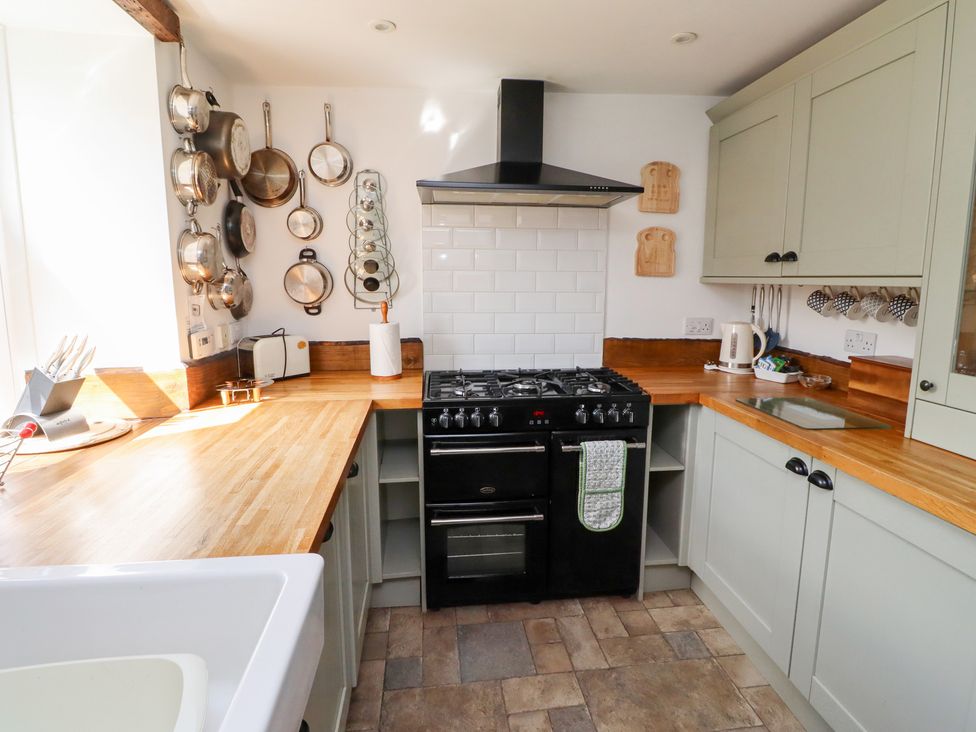 A kitchen with a stove, cabinets, sink, and kitchen utensils at Bruno's Bothy Middleton near Belford