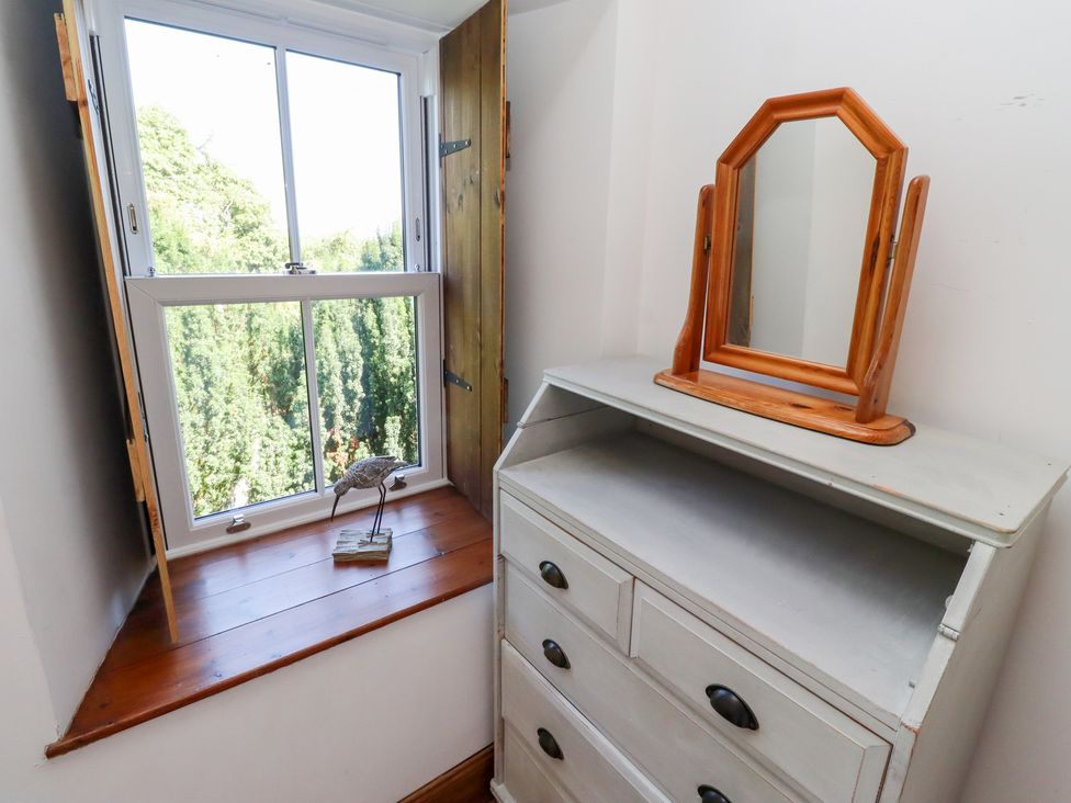 A bedroom with a window and a mirror at Bruno's Bothy Middleton near Belford