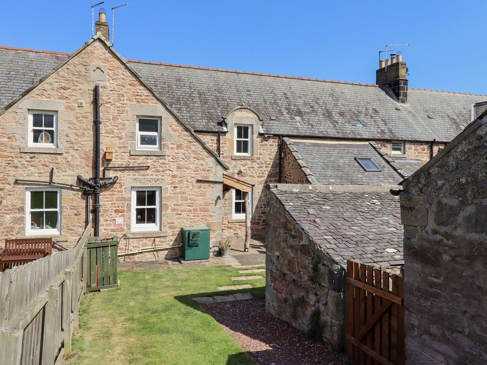 An outdoor view of a stone house and garden at Bruno's Bothy in Middleton near Belford