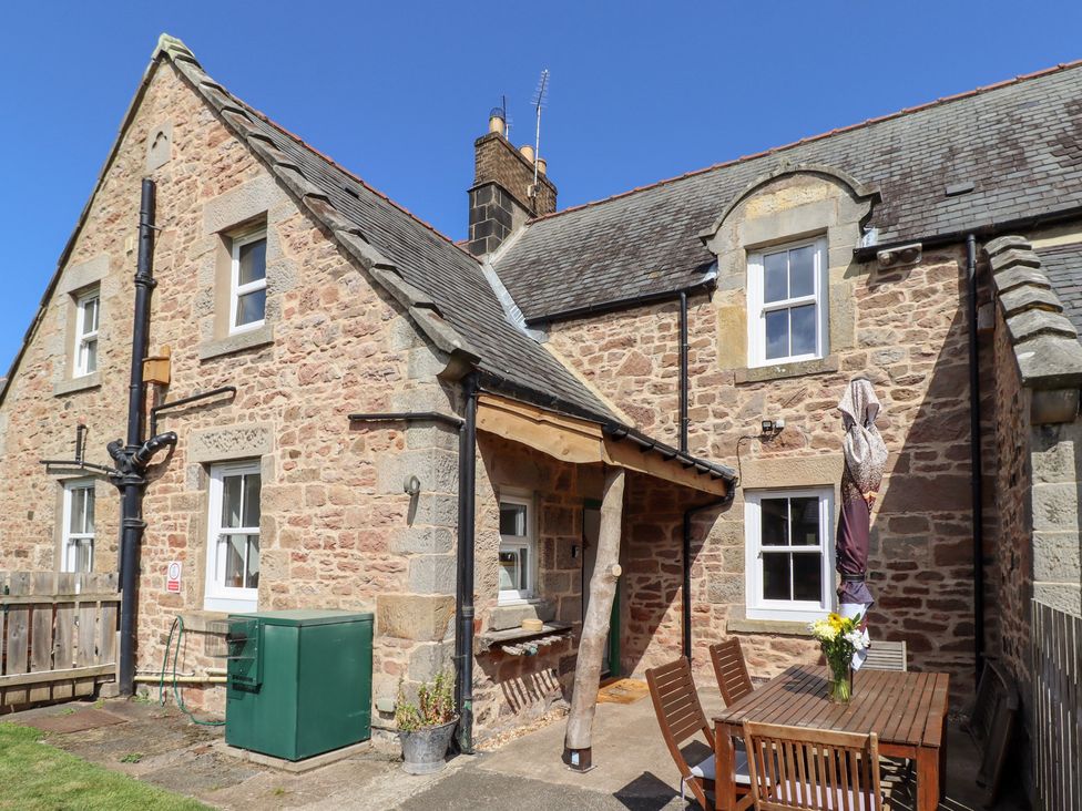 A stone exterior with a table and chairs at Bruno's Bothy in Middleton near Belford