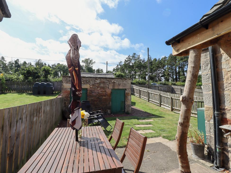 A garden with a table and chairs at Bruno's Bothy Middleton near Belford