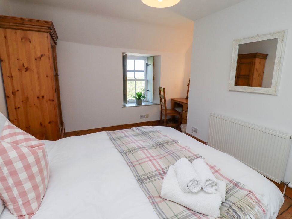 A bedroom with a bed and wardrobe at Kits Cottage Middleton near Belford