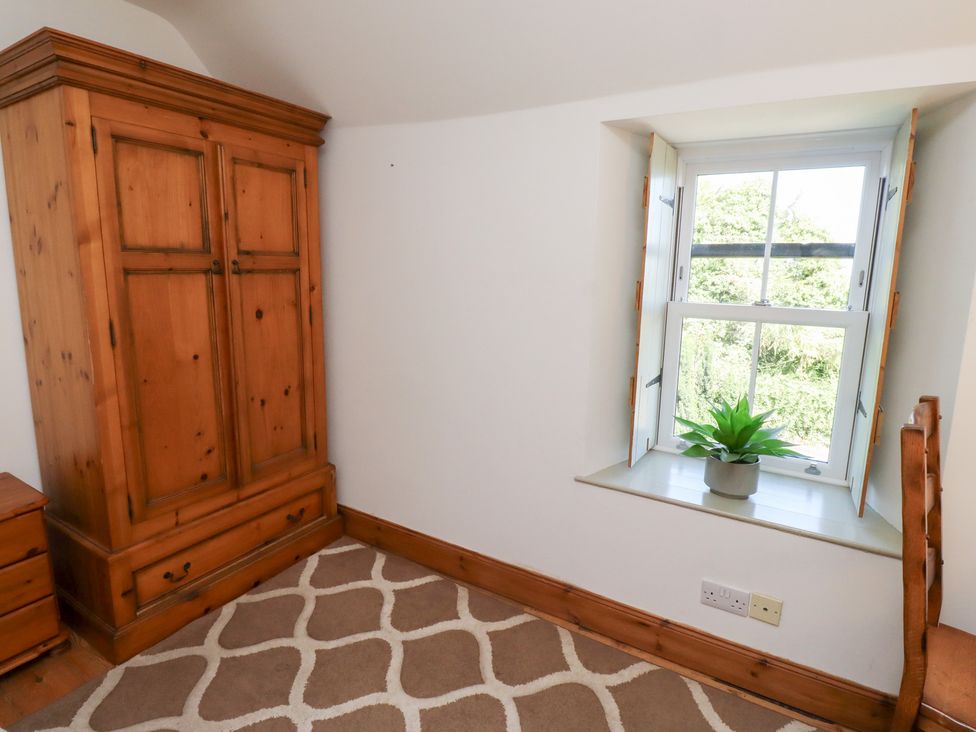 A bedroom with a wardrobe and window at Kits Cottage Middleton near Belford