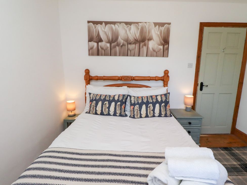 A bedroom with a bed and bedside table at Kits Cottage in Middleton near Belford