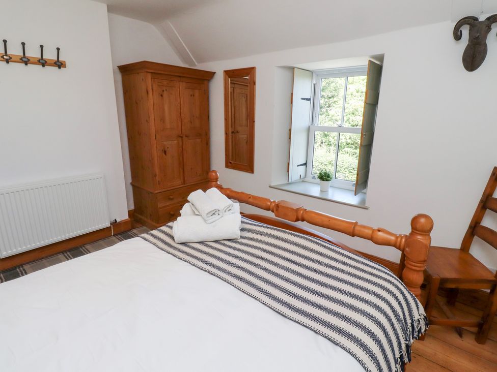 A bedroom with a bed and wardrobe at Kits Cottage in Middleton near Belford