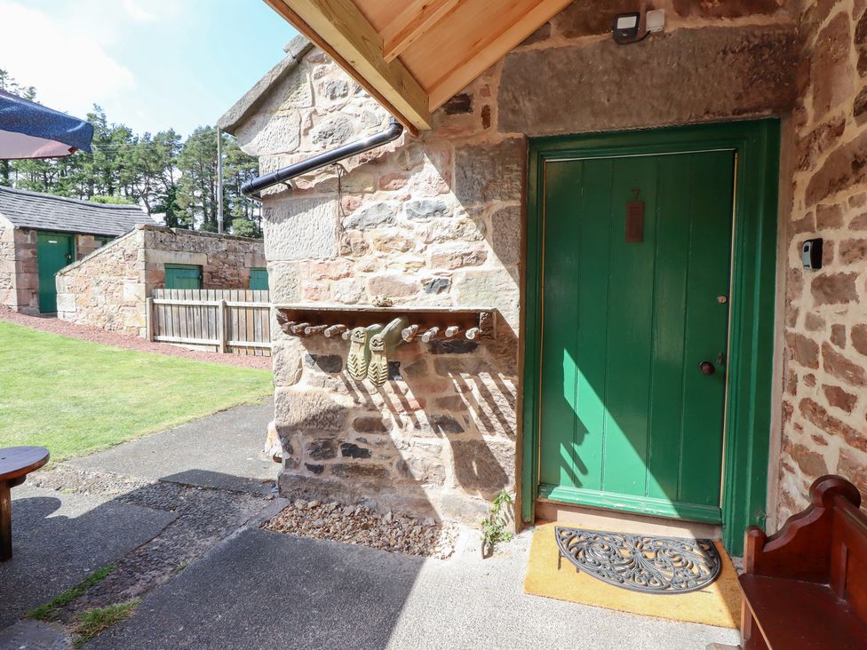 An entrance area with a green door and stone wall at Kits Cottage in Middleton near Belford