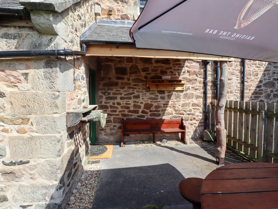 An outdoor area with a bench and stone wall at Kits Cottage Middleton near Belford