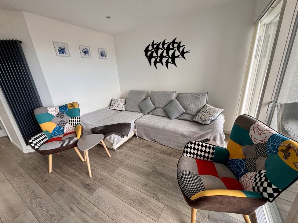 A living room with sofa and chairs at 10 Quay Court in Newquay