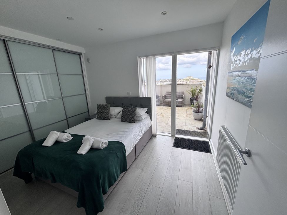 A bedroom with a bed and sliding doors at 10 Quay Court in Newquay
