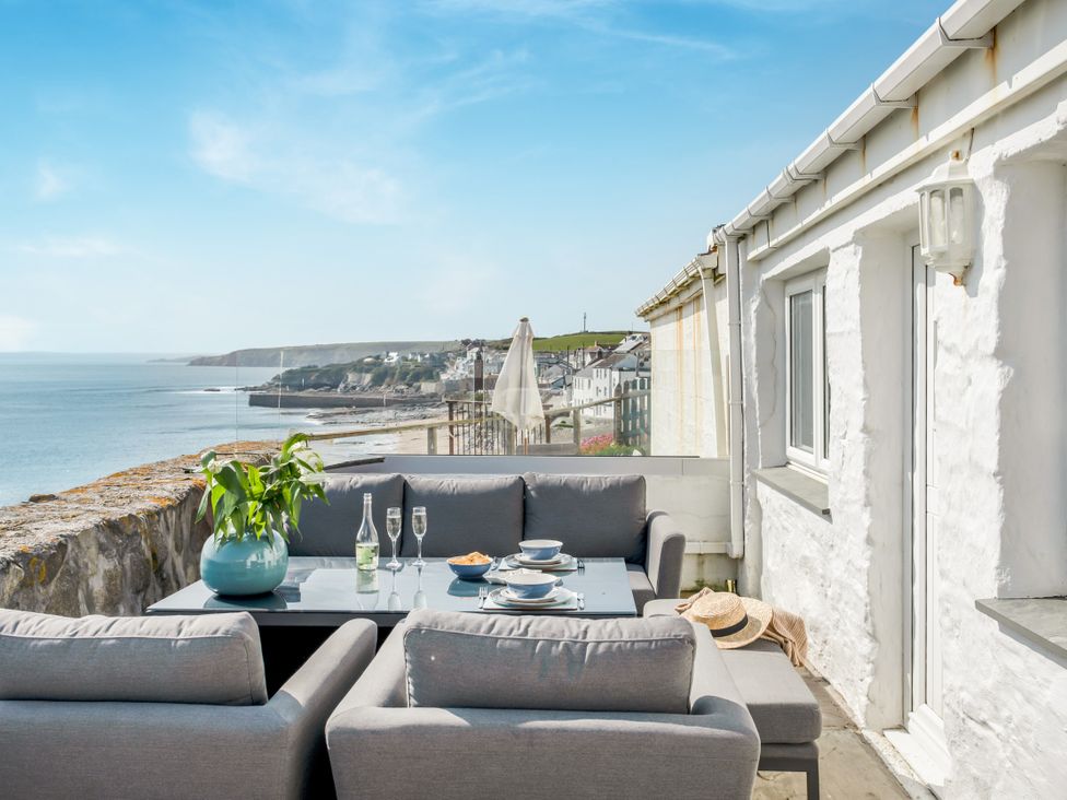 An outdoor seating area with a table and chairs overlooking the sea at Loe Cottage in Porthleven