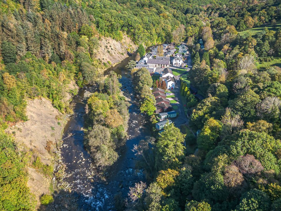 A view of houses along a river surrounded by trees at Apartment 1 in Keswick
