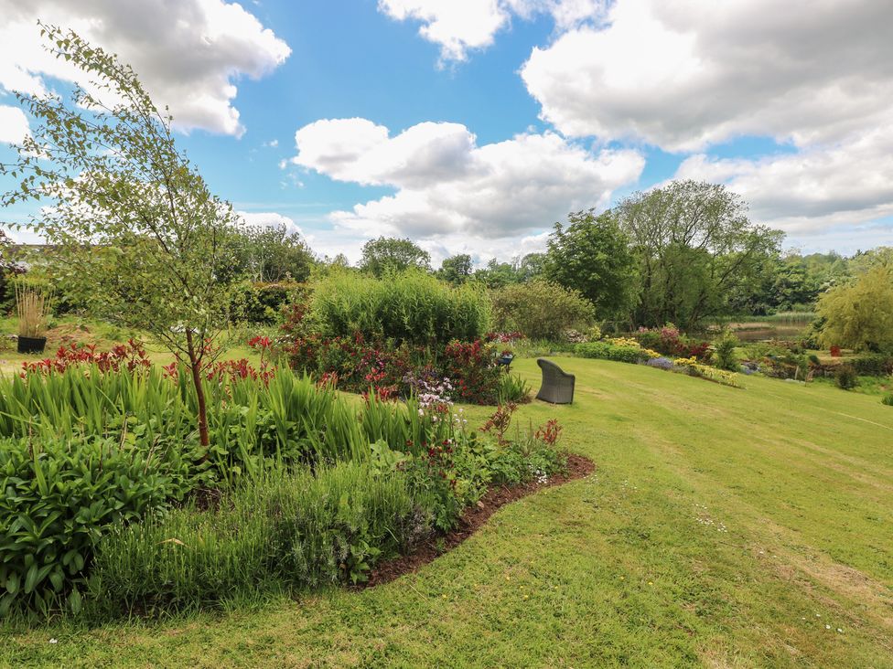 A garden with flowers, grass and a chair at Garden View in Pembroke