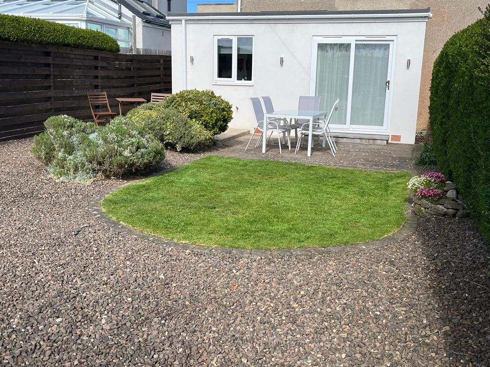 A garden with grass and a patio set at Maywood in Seahouses