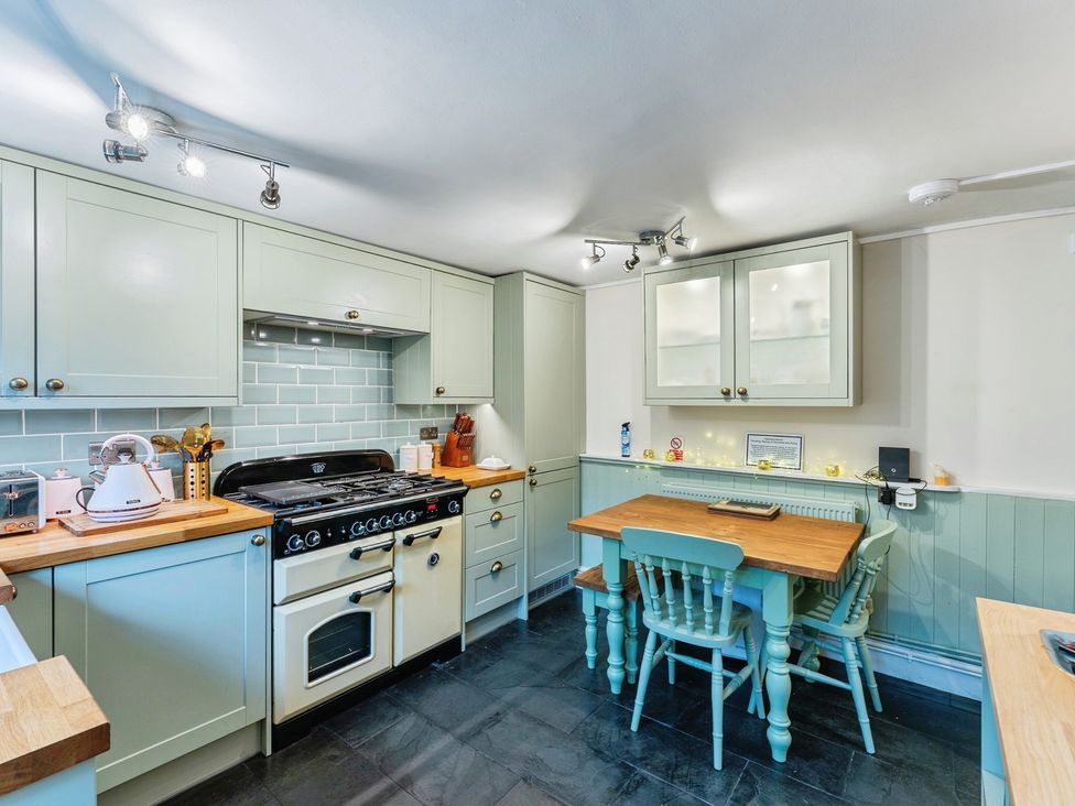 A kitchen with stove, countertops and table at Rivendell in Ffynnongroyw