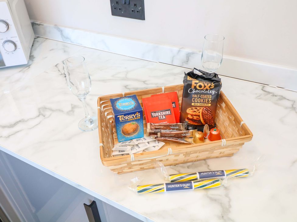 A kitchen countertop with a basket of snacks and glasses at Apt 9 @ Hunter's Quay Bridlington