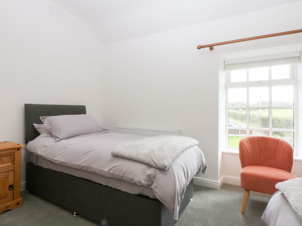 A bedroom with two beds and a chair at Trefor Ganol Beaumaris